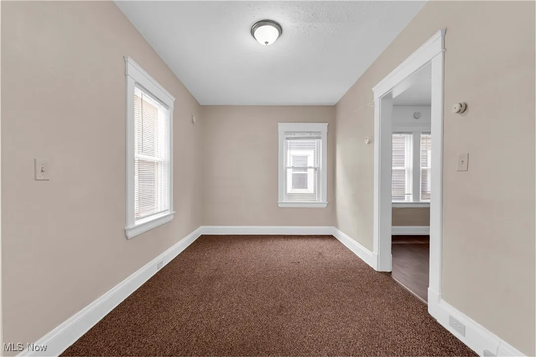 Unfurnished room with dark colored carpet and a smoke detector