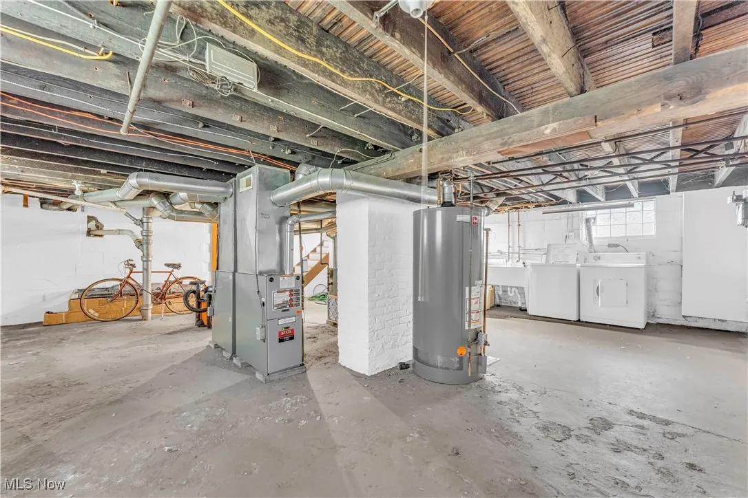 Basement with water heater, separate washer and dryer, and heating unit