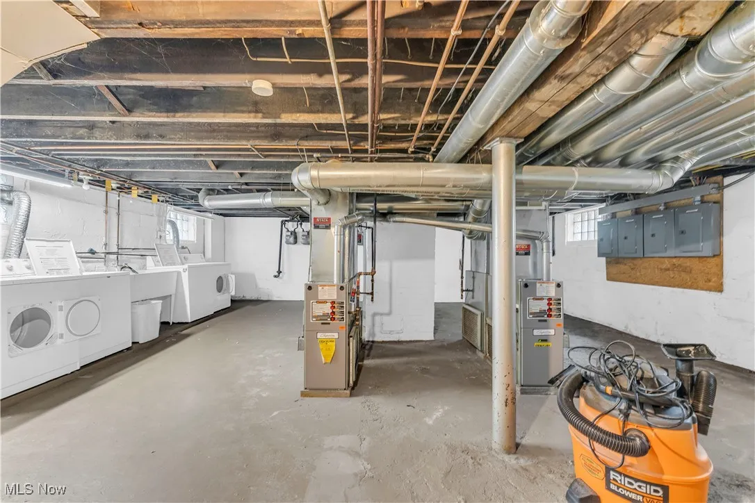 Basement with washer and clothes dryer, heating unit, and electric panel