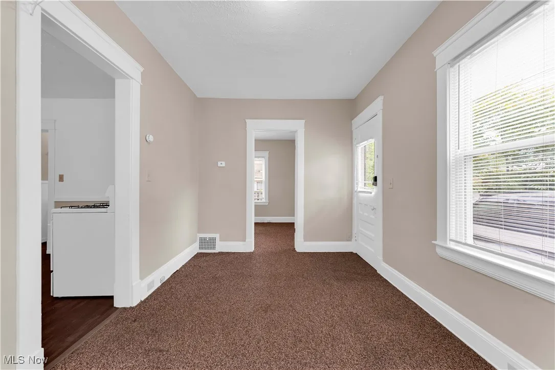 Empty room with baseboards and dark carpet