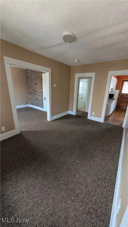 Unfurnished room with a textured ceiling and dark carpet