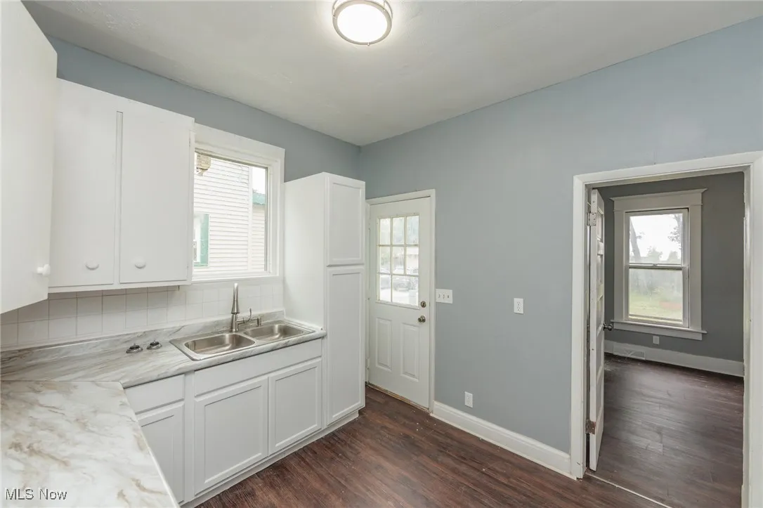 Kitchen with white cabinets, dark wood-style floors, light countertops, and tasteful backsplash