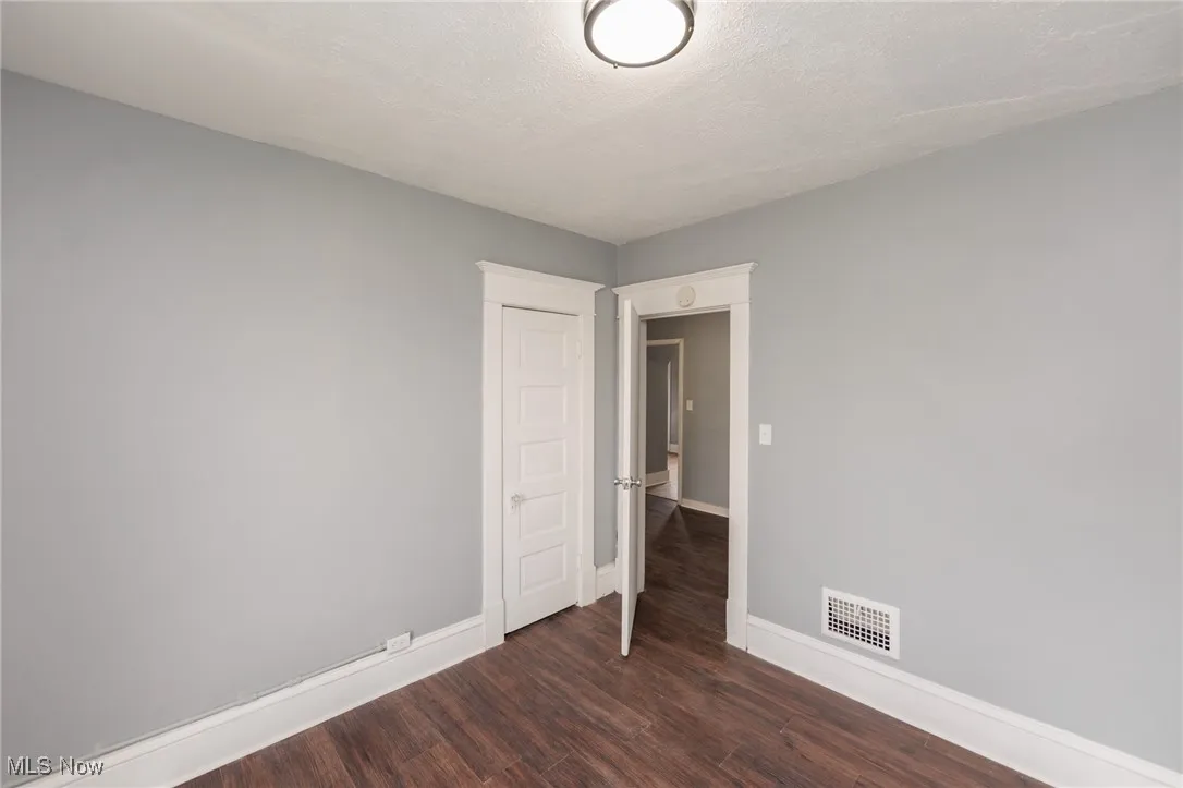 Unfurnished room featuring dark wood-style floors and a textured ceiling
