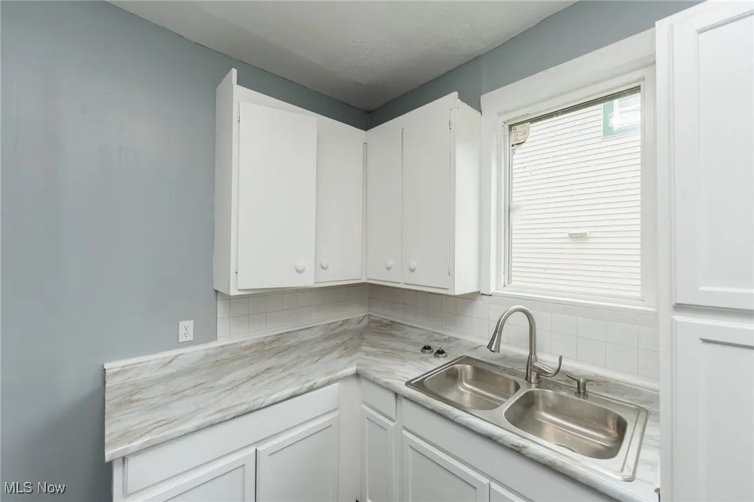 Kitchen featuring white cabinets, light countertops, and backsplash