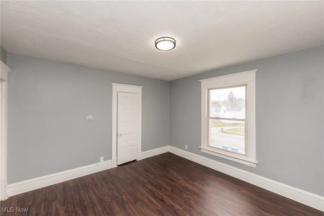 Empty room with dark wood-style flooring and a textured ceiling