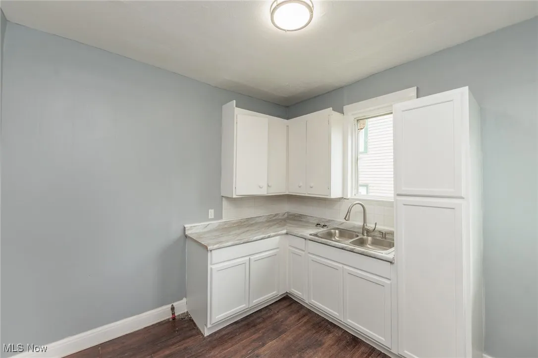 Kitchen featuring dark wood finished floors, white cabinets, and light countertops