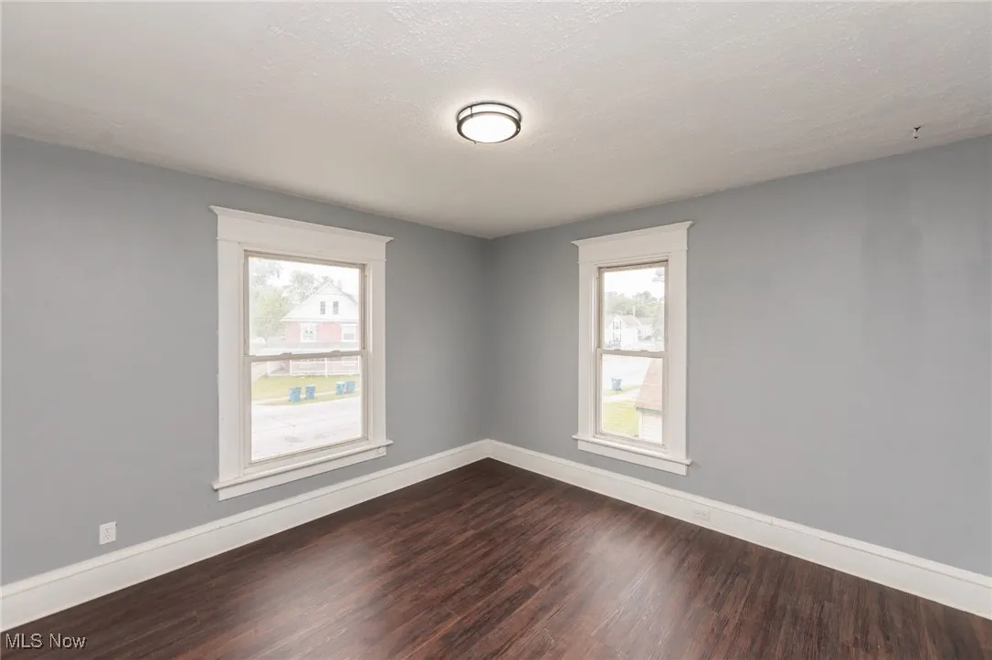 Unfurnished room featuring dark wood-style flooring and baseboards