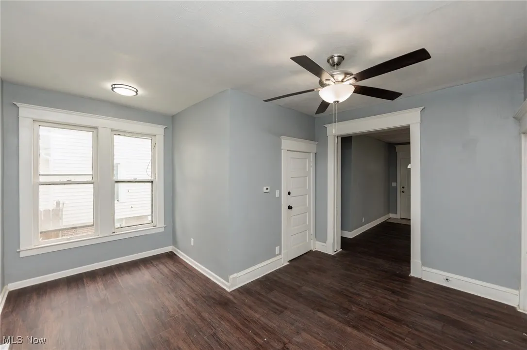 Unfurnished room with ceiling fan and dark wood finished floors
