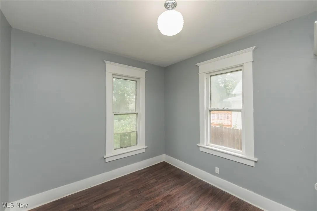 Spare room with baseboards and dark wood-type flooring