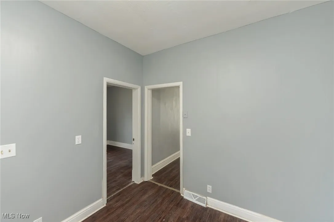 Spare room with dark wood-style floors and baseboards