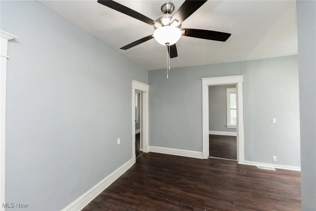 Spare room with dark wood-style flooring and a ceiling fan