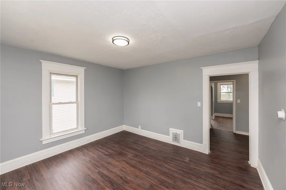 Spare room featuring dark wood-style flooring and​​‌​​​​‌​​‌‌​‌‌​​​‌‌​‌​‌​‌​​​‌​​ baseboards