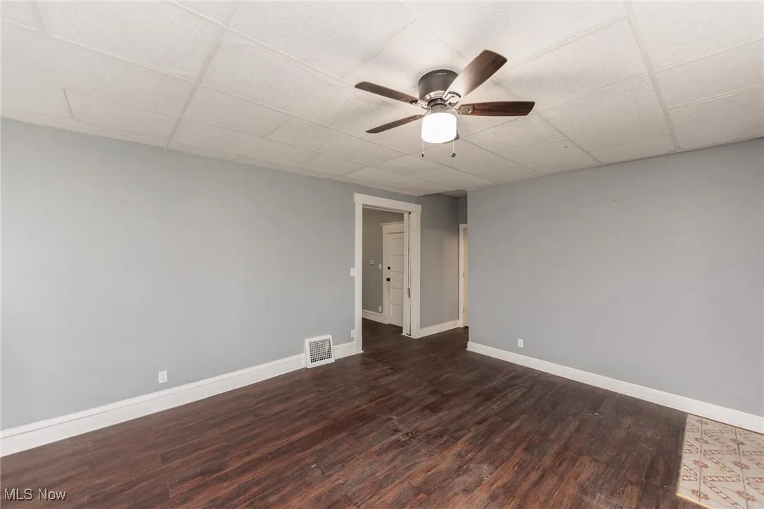 Spare room with dark wood finished floors, a ceiling fan, and a drop ceiling