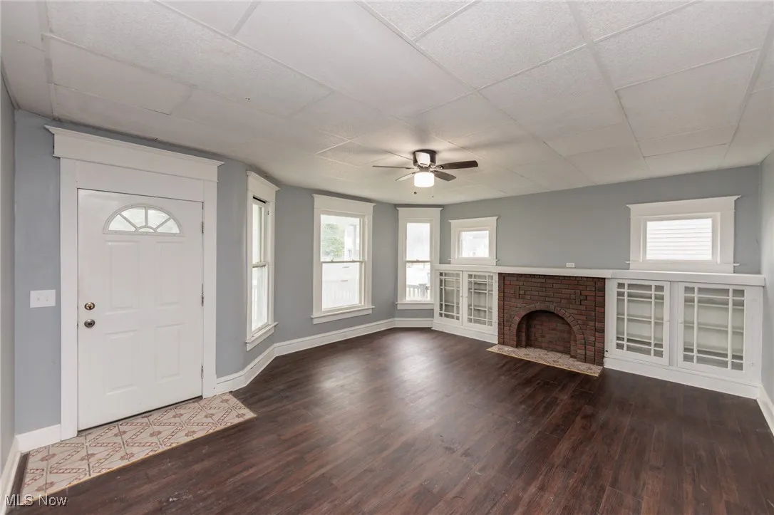 Entryway with a ceiling fan, wood finished floors, a drop ceiling, and a fireplace