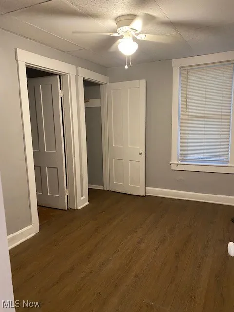 Unfurnished bedroom with dark wood-style flooring and ceiling fan