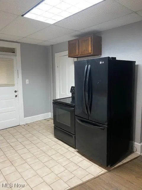 Kitchen with black appliances, a paneled ceiling, and light wood-style flooring