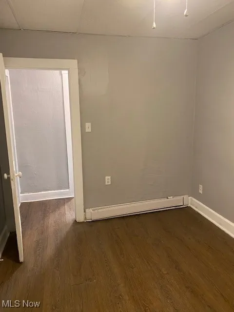 Empty room featuring dark wood-style flooring and baseboard heating