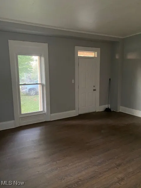 Empty room with dark wood-style flooring and ornamental molding