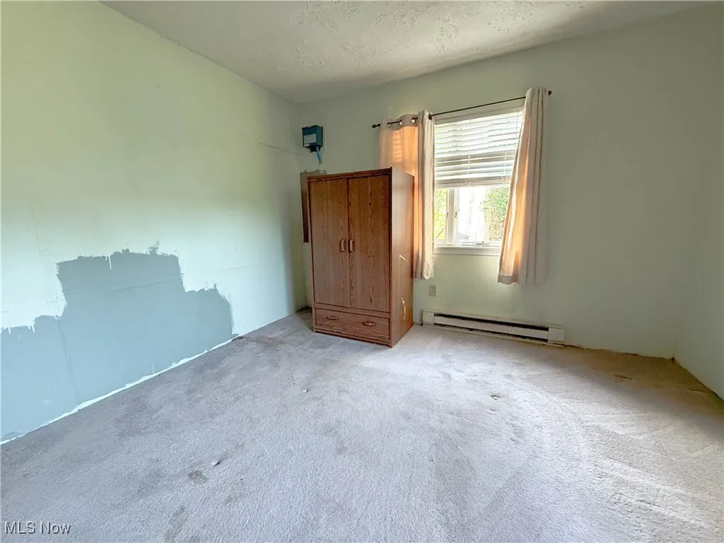 Unfurnished bedroom featuring baseboard heating, carpet flooring, and a textured ceiling