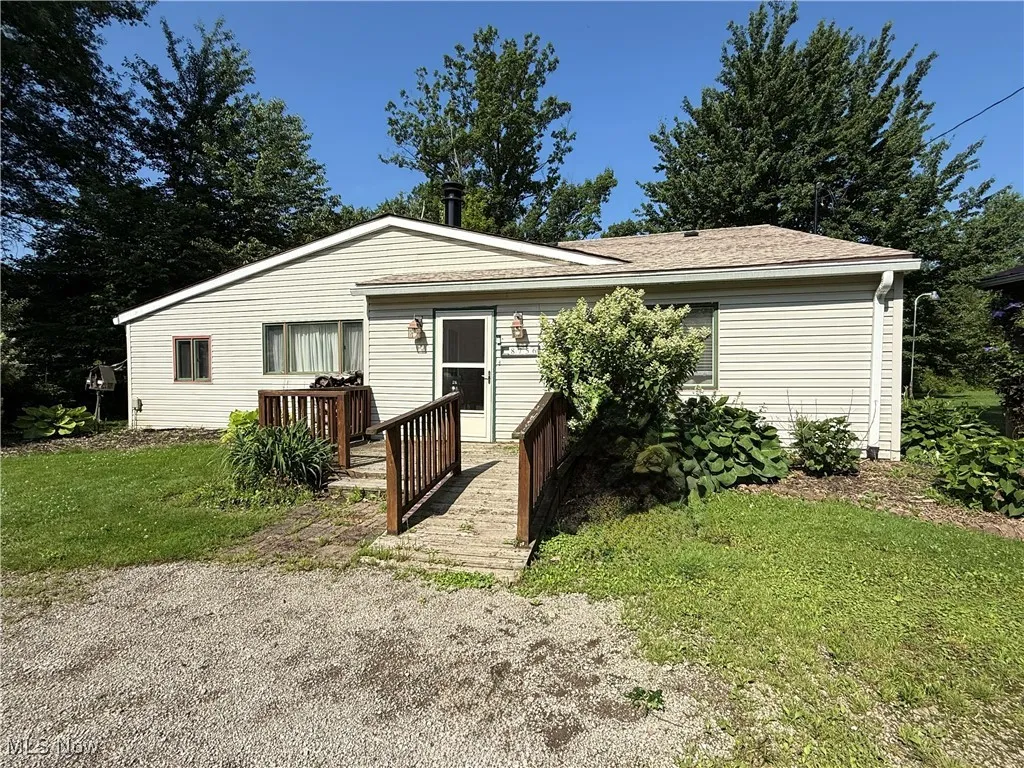 View of front facade with a front yard and a wooden deck