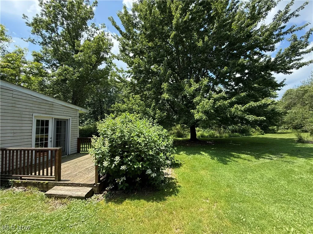 View of grassy yard with a wooden deck and french doors