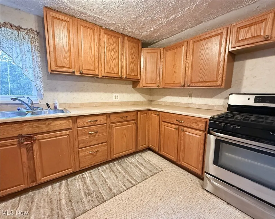 Kitchen featuring gas stove, light countertops, and a textured ceiling