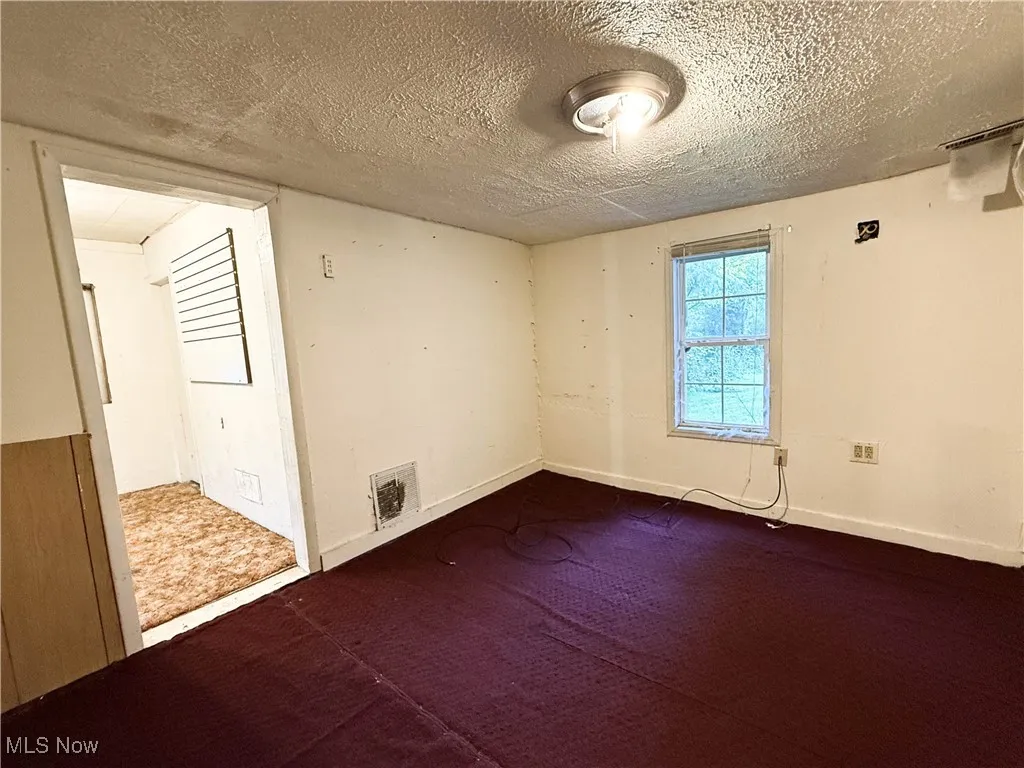 Spare room featuring a textured ceiling and dark colored carpet