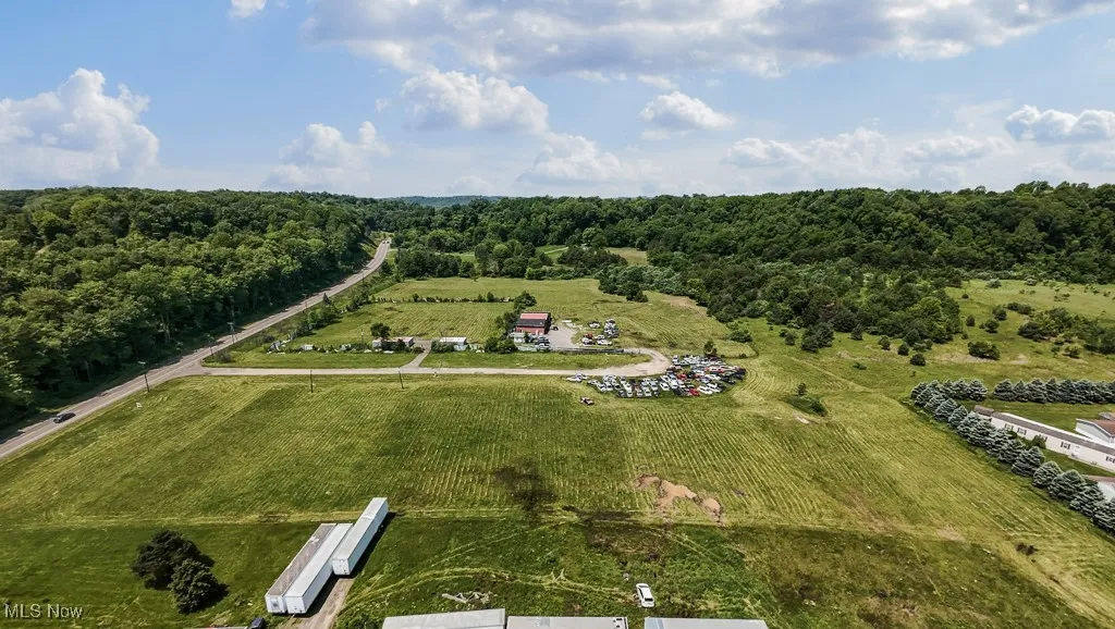 Aerial view of property and surrounding area featuring a forest and rural landscape