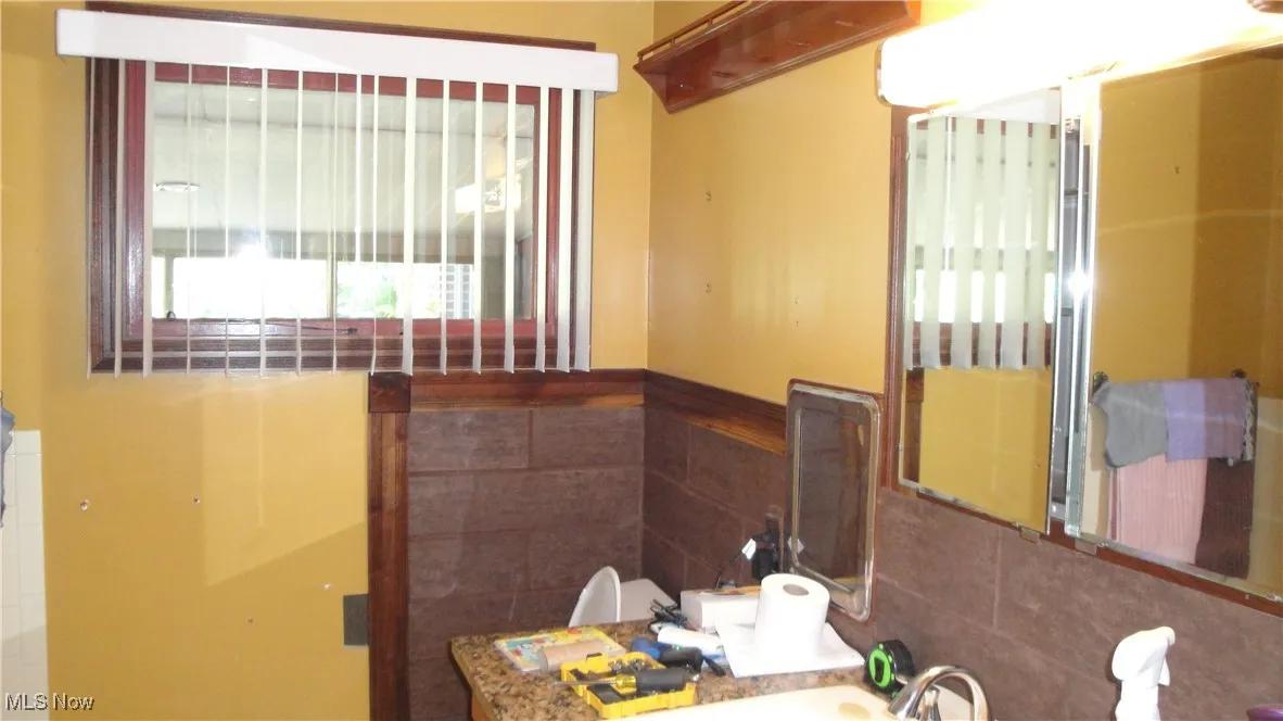 Bathroom with tile walls, wainscoting, and vanity