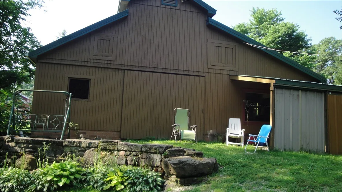 View of side of home featuring a barn and a yard