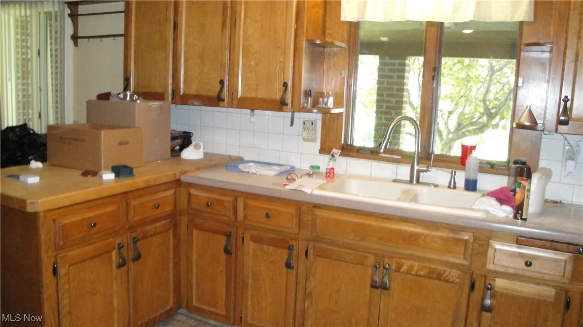 Kitchen featuring tasteful backsplash, light countertops, brown cabinets, and a peninsula