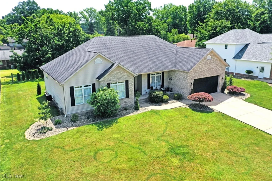 Single story home featuring an attached garage, a front lawn, driveway, and brick siding