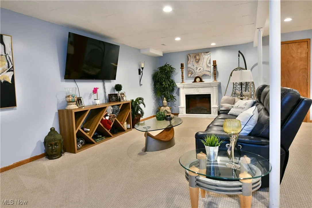 Living room with carpet flooring, a glass covered fireplace, and recessed lighting