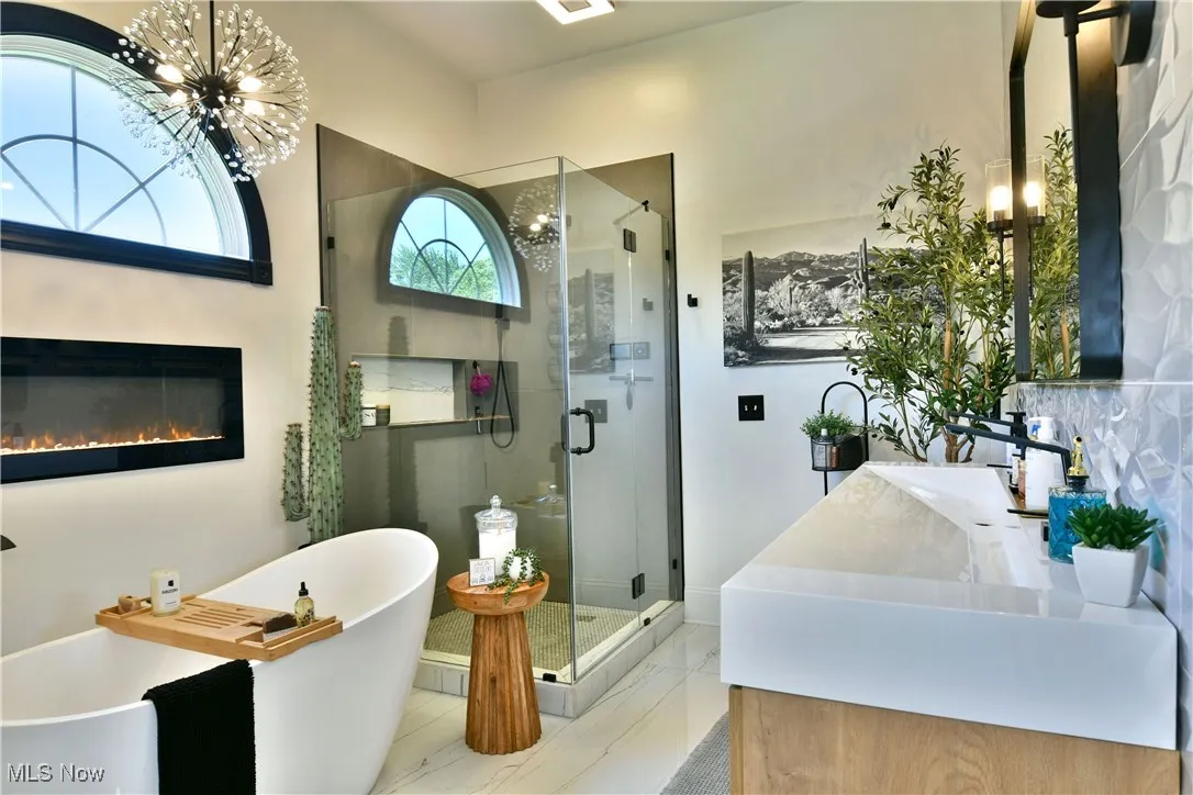 Bathroom featuring a chandelier, a shower stall, and a soaking tub