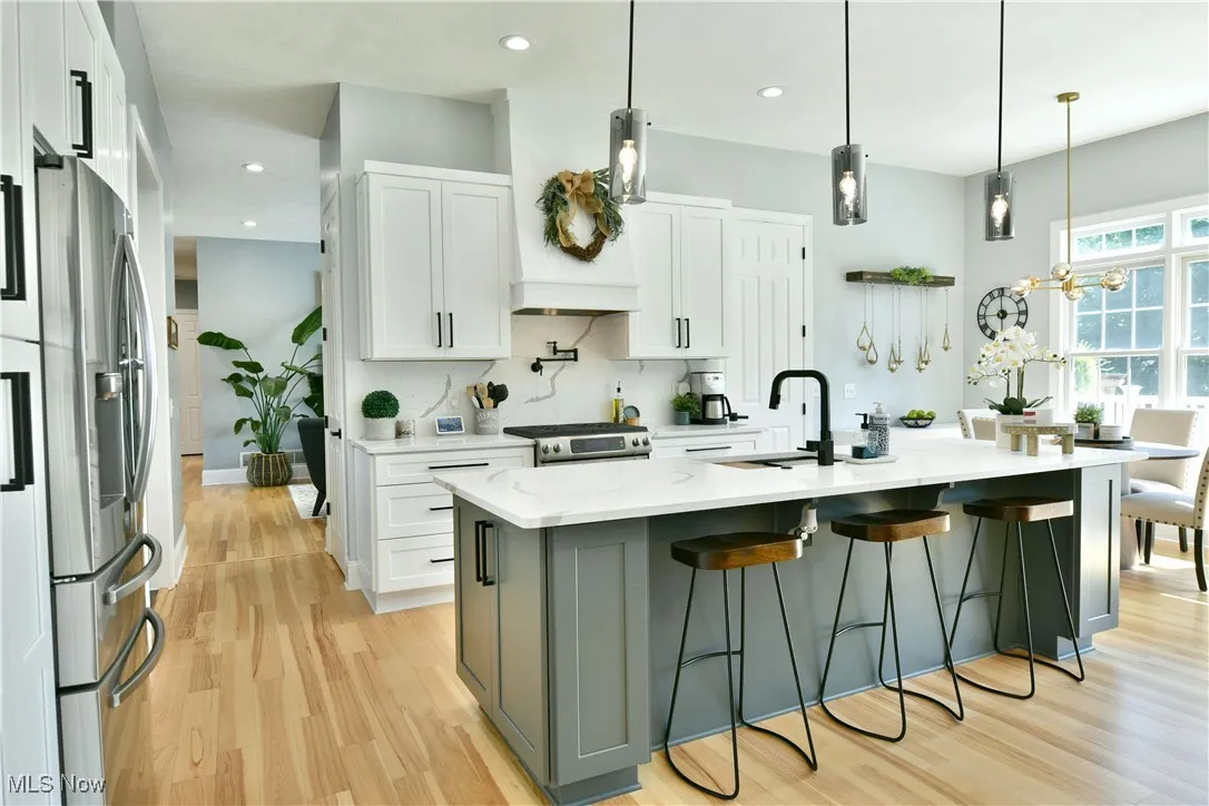 Kitchen featuring stainless steel appliances, white cabinets, light wood finished floors, a breakfast bar area, and recessed lighting