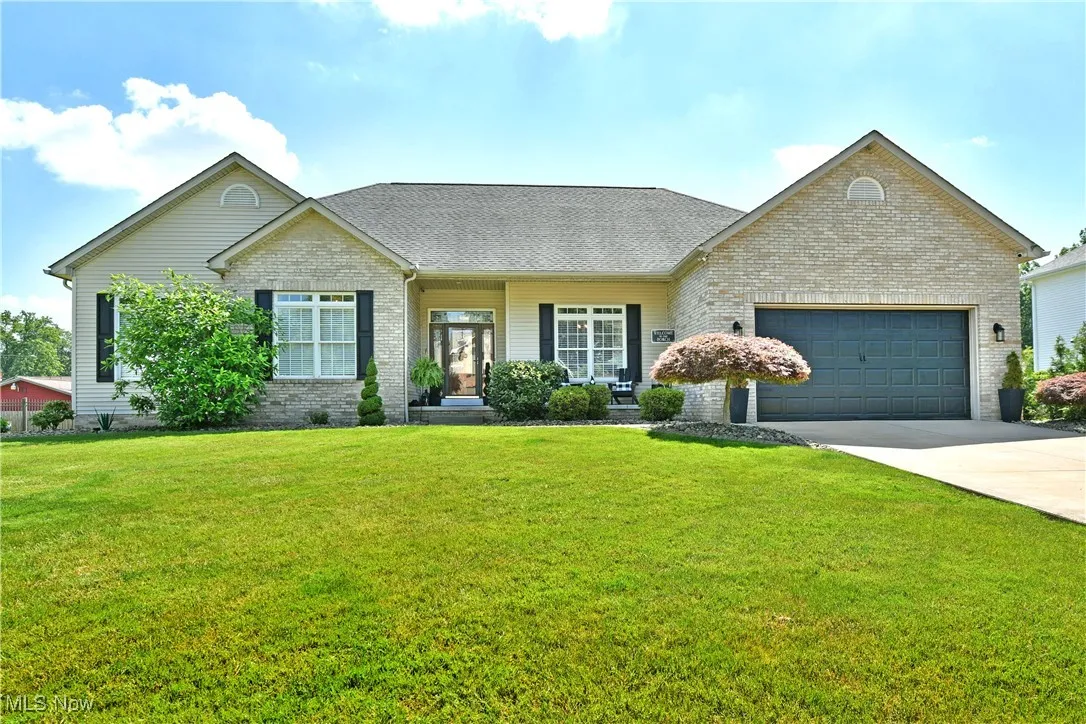 View of front of property with brick siding, a garage, a front lawn, and concrete driveway