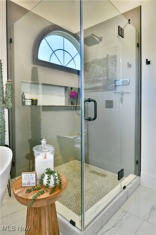 Bathroom with a stall shower and marble look tiles
