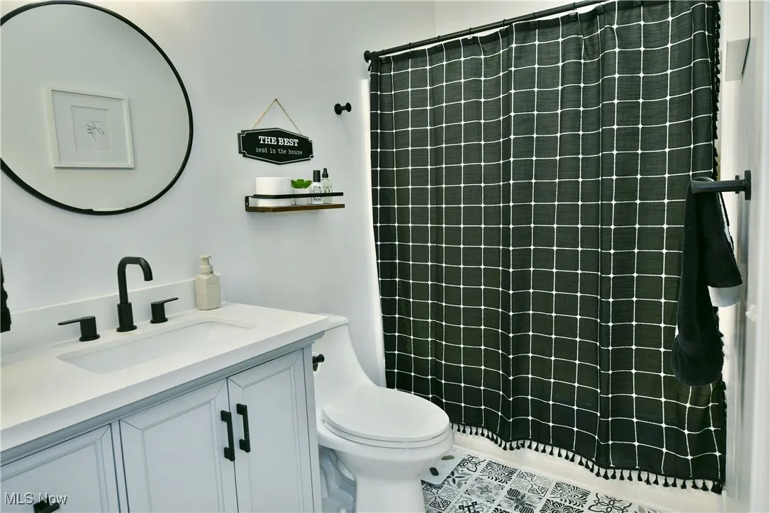 Full bathroom with vanity, tiled shower, and tile patterned flooring