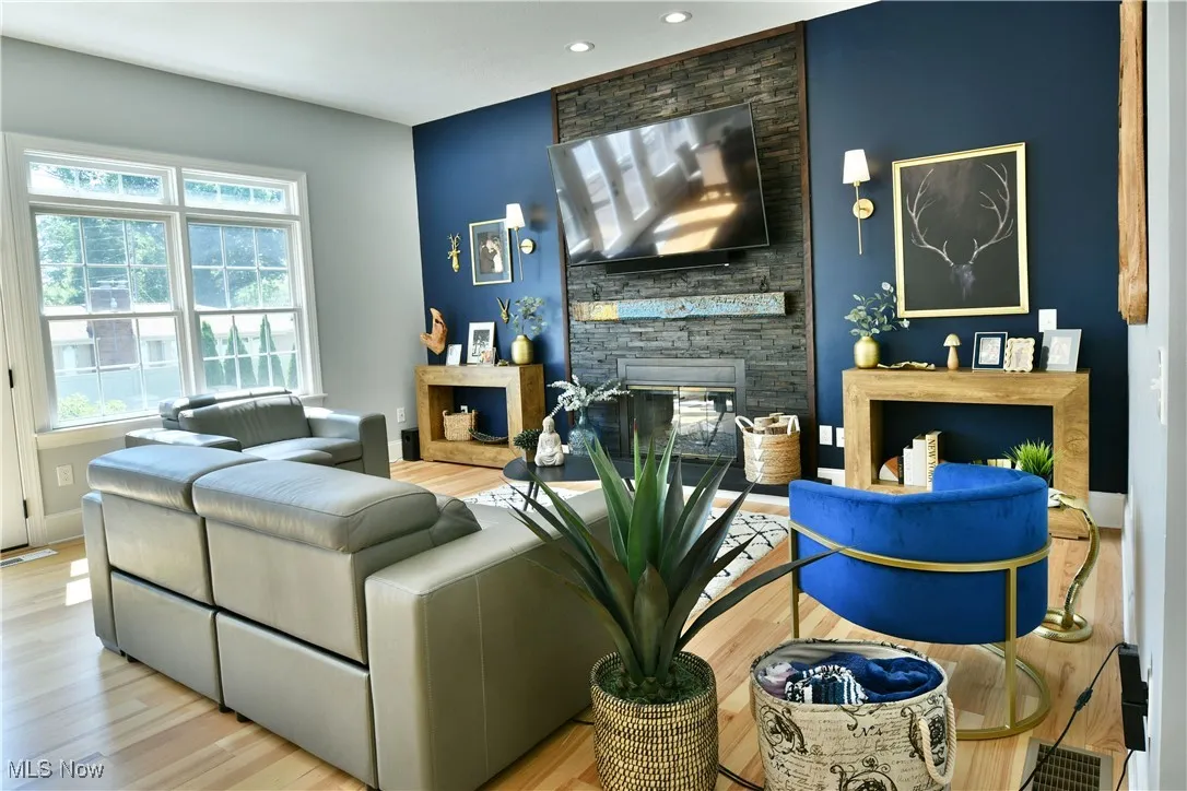 Living area featuring healthy amount of natural light, wood finished floors, a stone fireplace, and recessed lighting