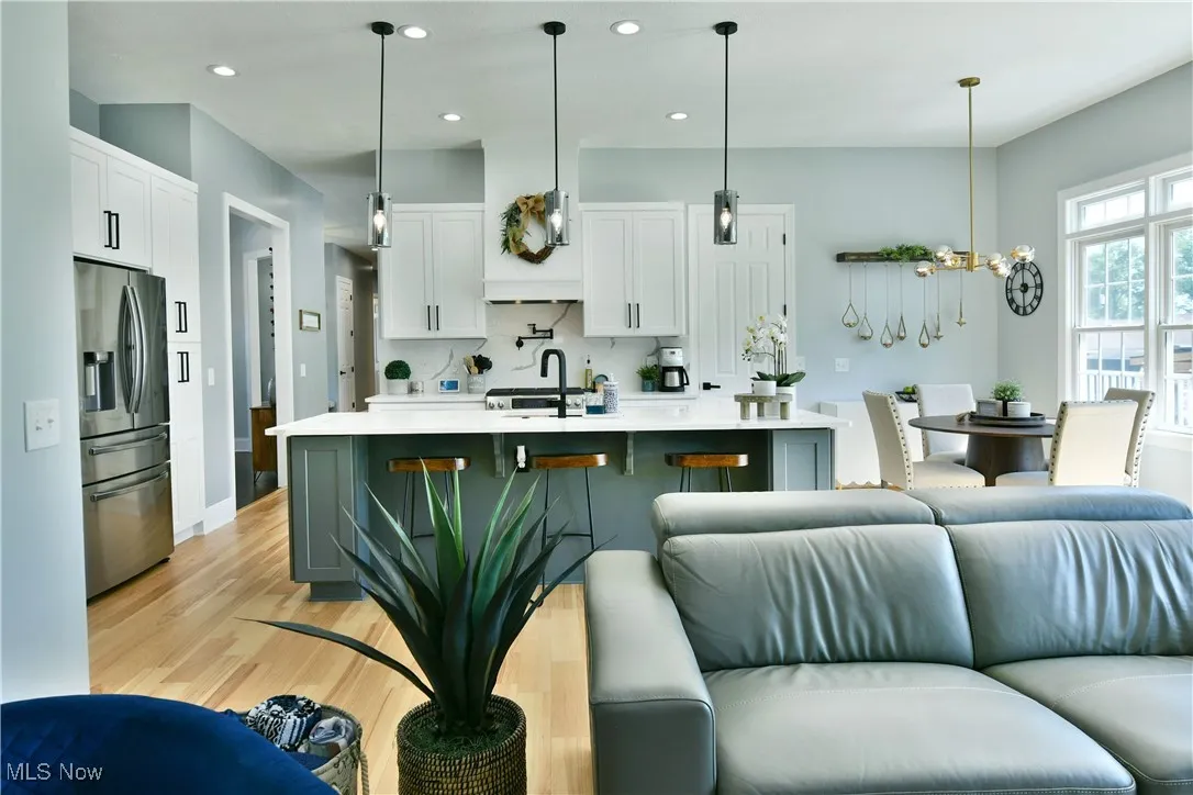 Kitchen with stainless steel fridge with ice dispenser, open floor plan, light countertops, light wood-type flooring, and recessed lighting