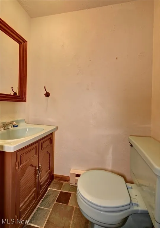 Bathroom with vanity, a baseboard heating unit, and stone finish flooring