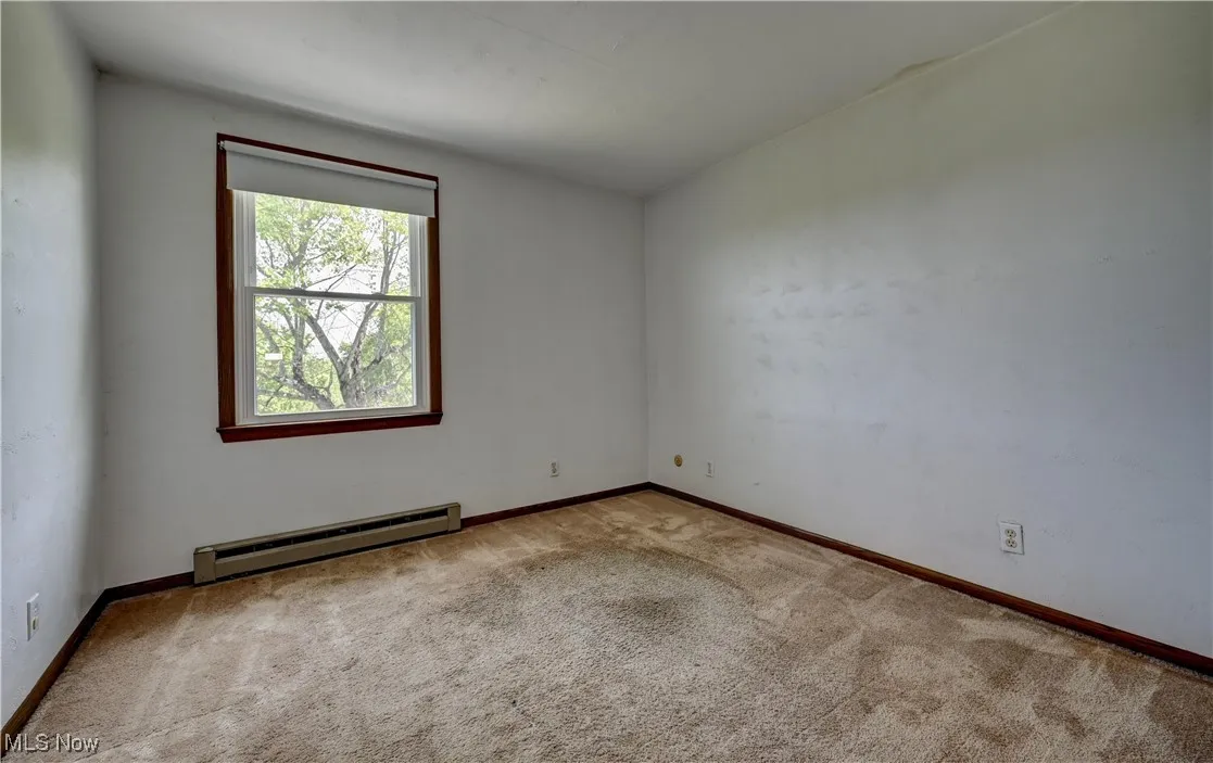 Carpeted spare room with baseboard heating and baseboards