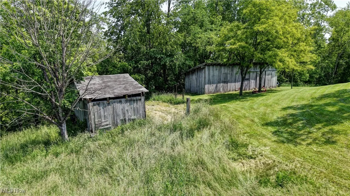 View of green lawn with a pole building and an outbuilding