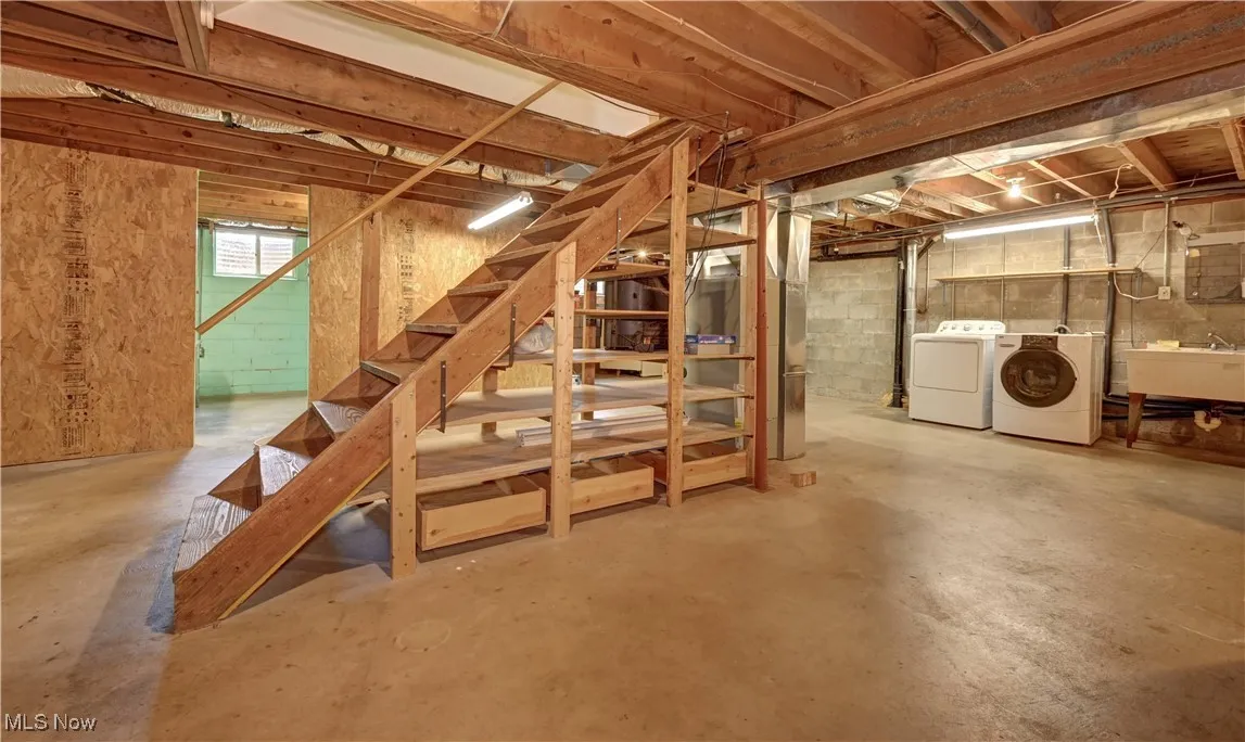 Basement featuring separate washer and dryer, stairway, and concrete block wall