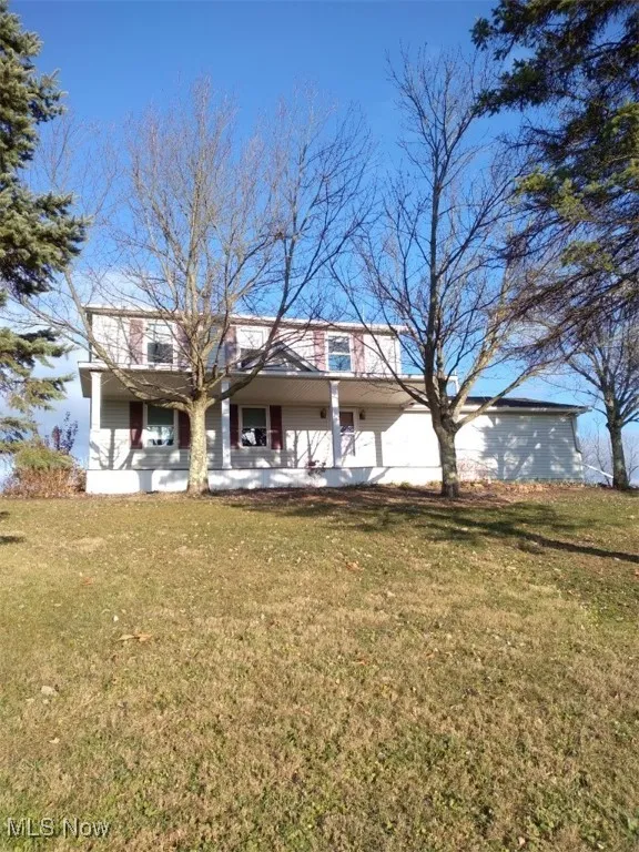 Rear view of house with covered porch, a lawn, and a garage