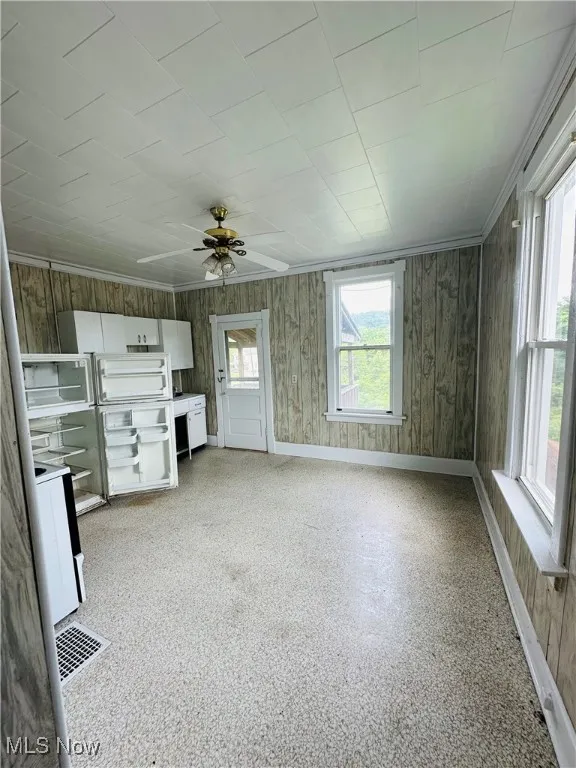 Unfurnished living room featuring baseboards and ceiling fan