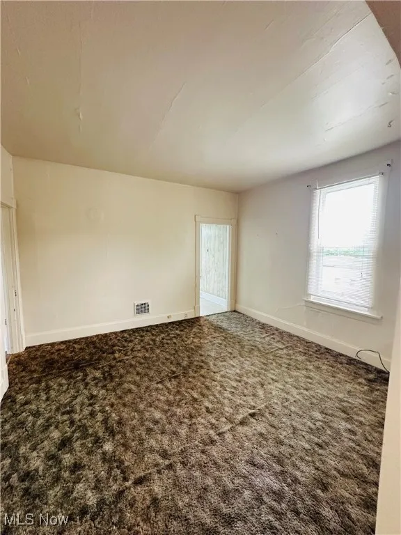 Carpeted spare room featuring baseboards