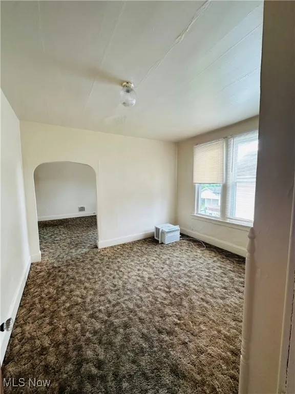 Spare room with carpet floors and arched walkways