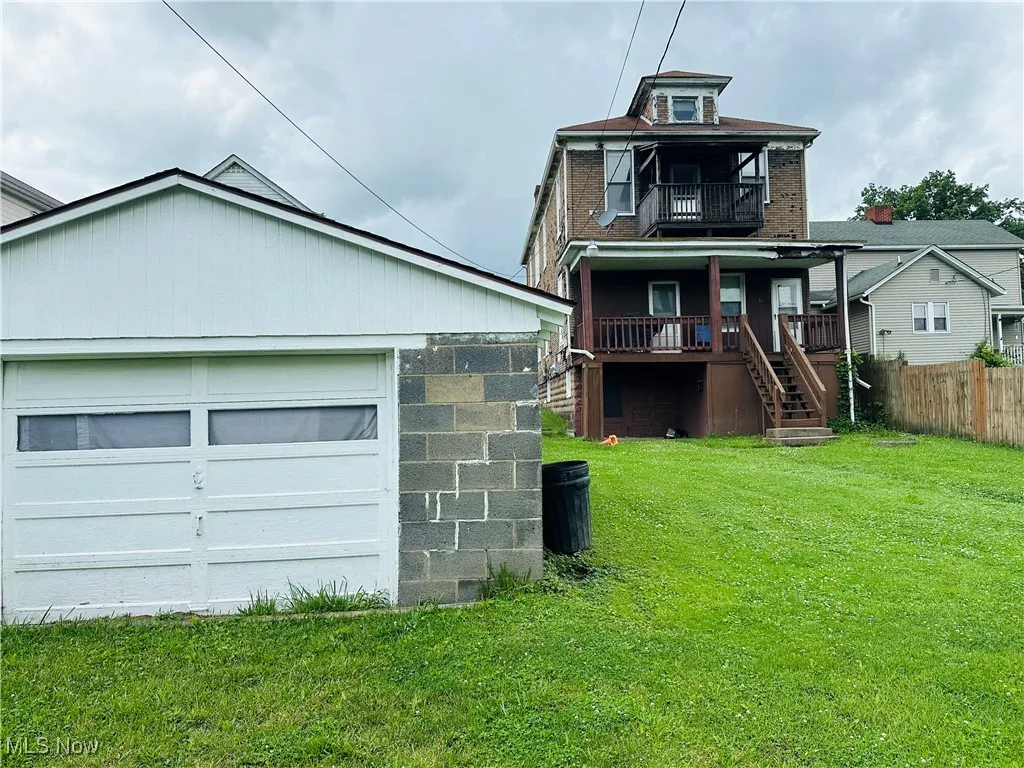 View of front of home featuring stairway, a balcony, a porch, and a detached garage