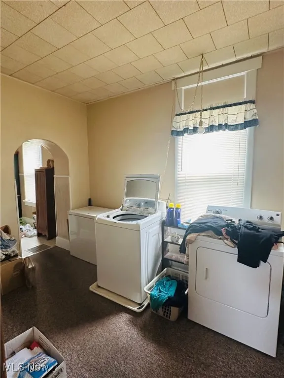 Laundry room with arched walkways, independent washer and dryer, and carpet floors